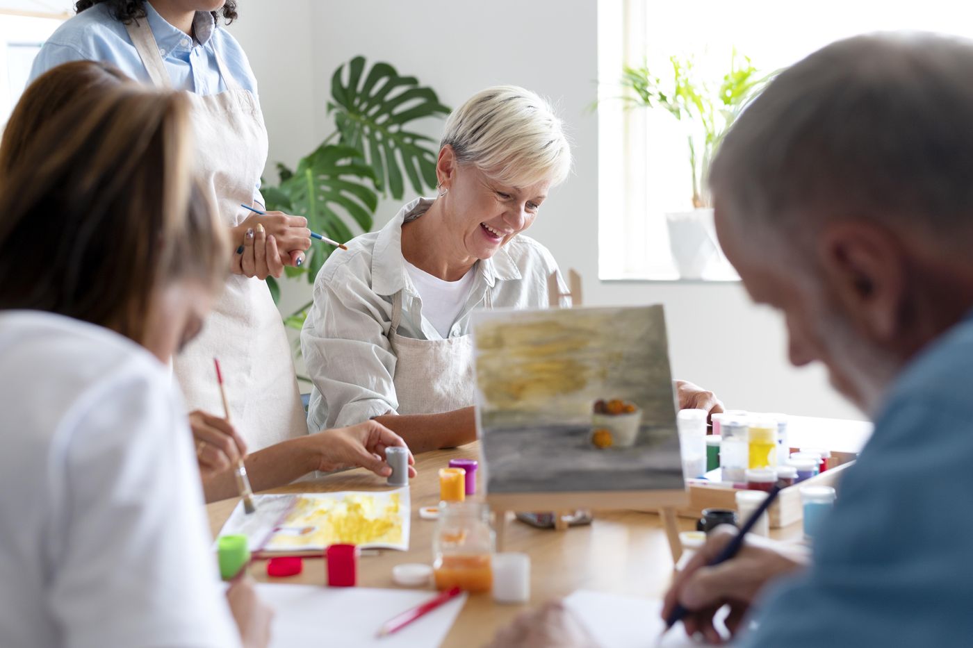 Residents painting together at a bright table with an easel