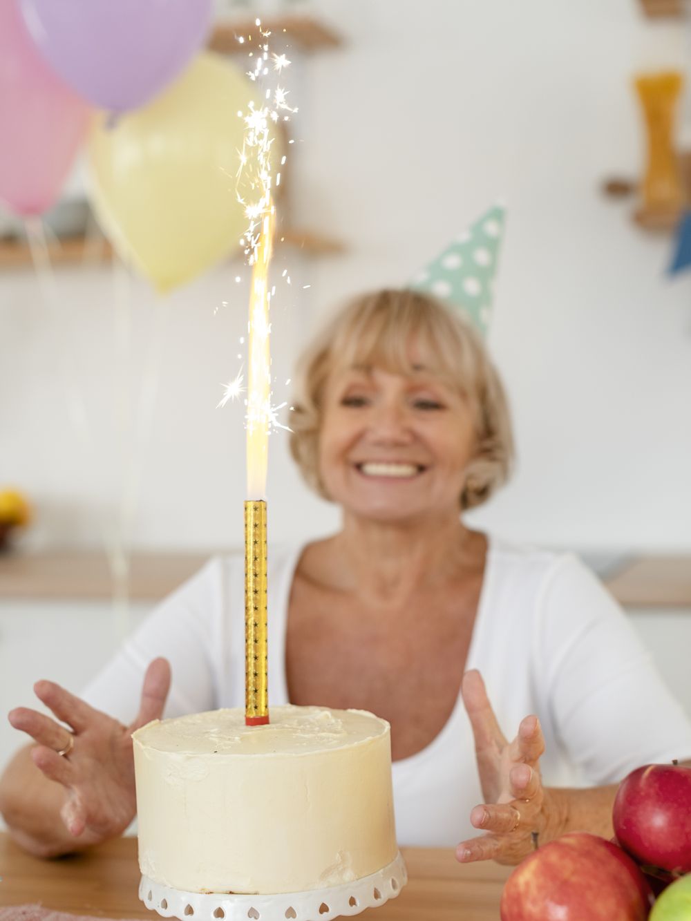 A resident smiling behind a birthday cake with a lit sparkler candle