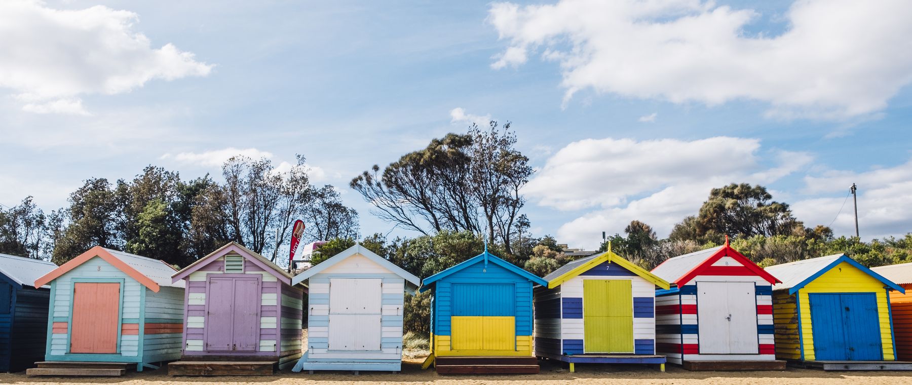 A row of colourful beach huts on the seafront under a blue sky