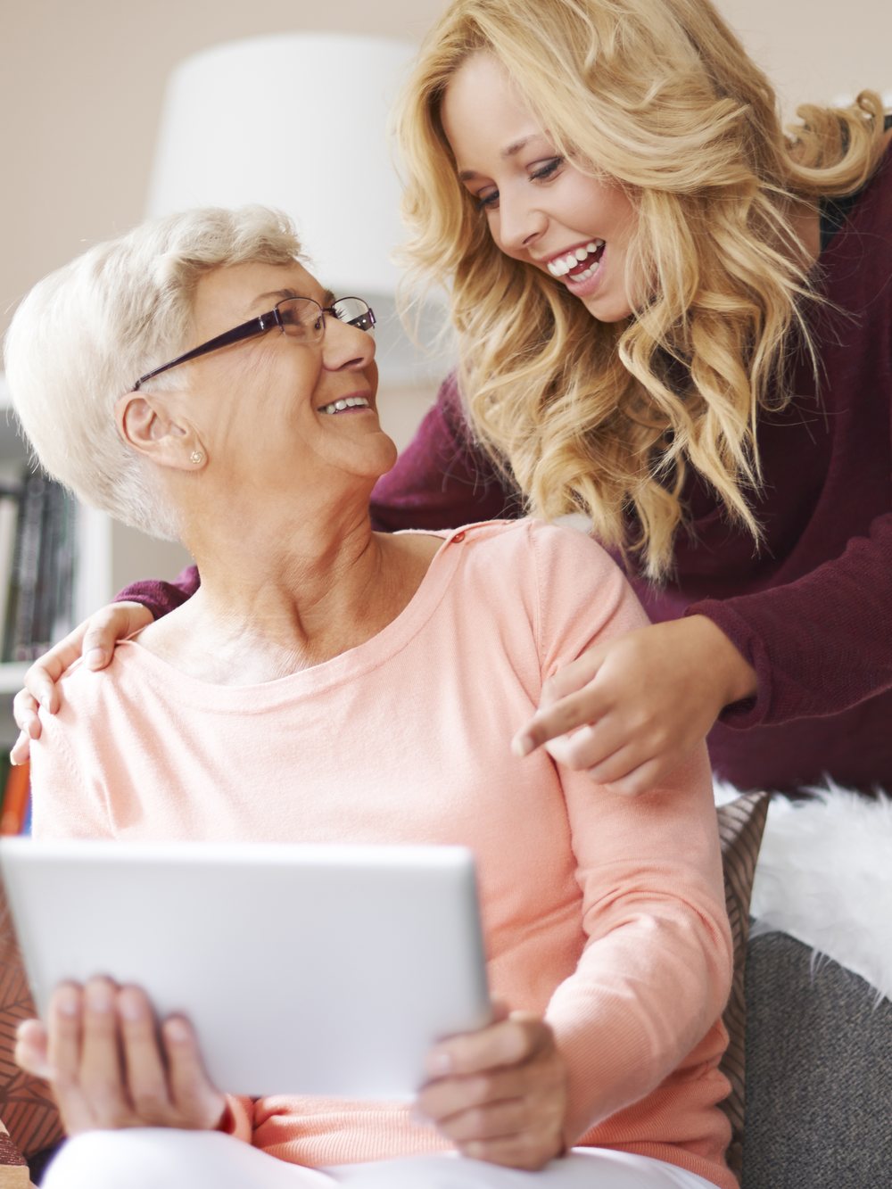 A resident and her daughter laughing together over something on a tablet