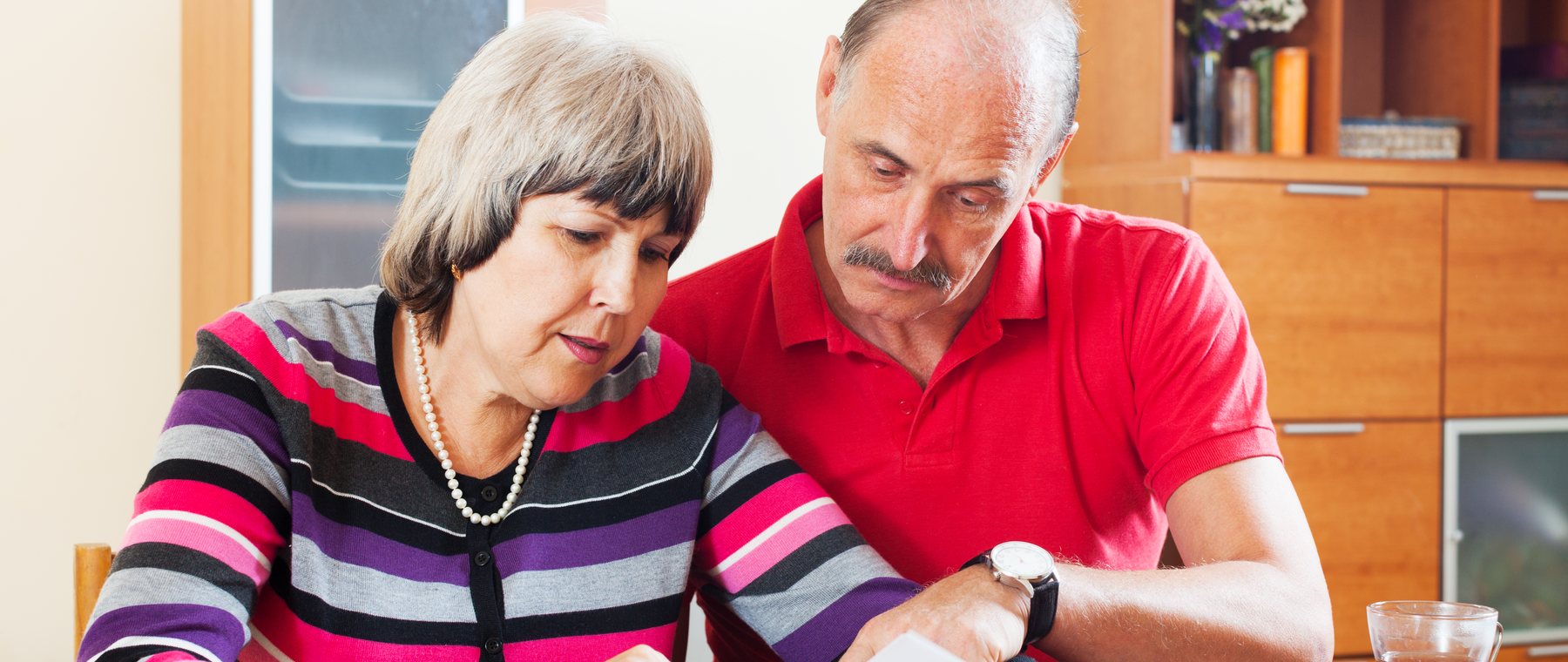 A couple at their kitchen table reading through paperwork together