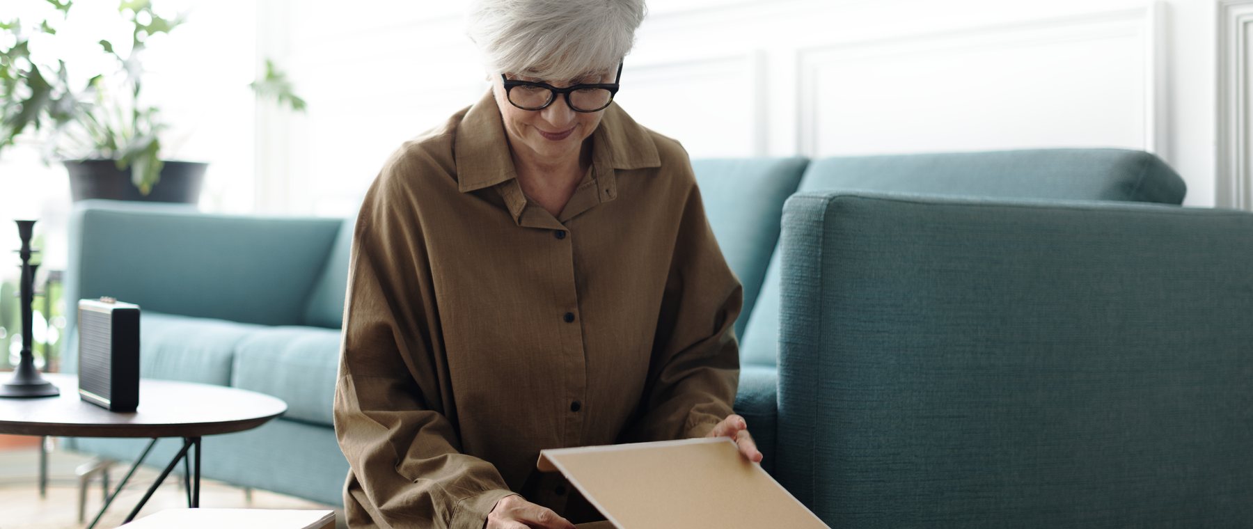 A woman in her living room lifting a picture out of a moving box