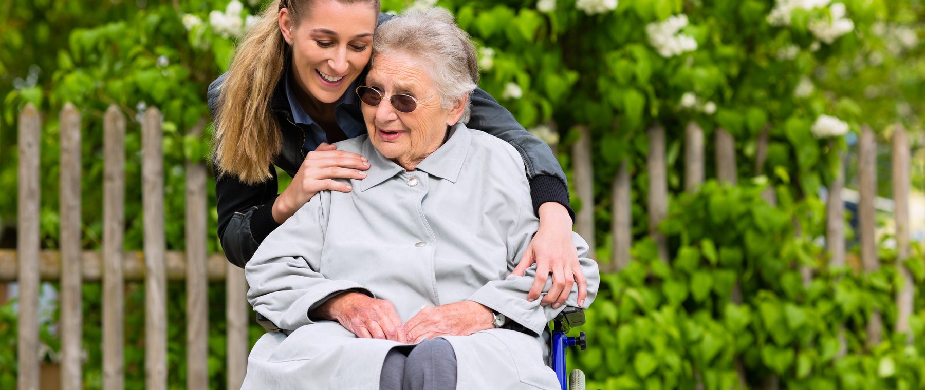 A granddaughter visiting her grandmother in the garden, arms round her shoulders