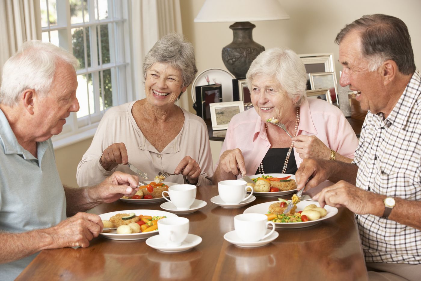 Four residents enjoying lunch together around a laid table