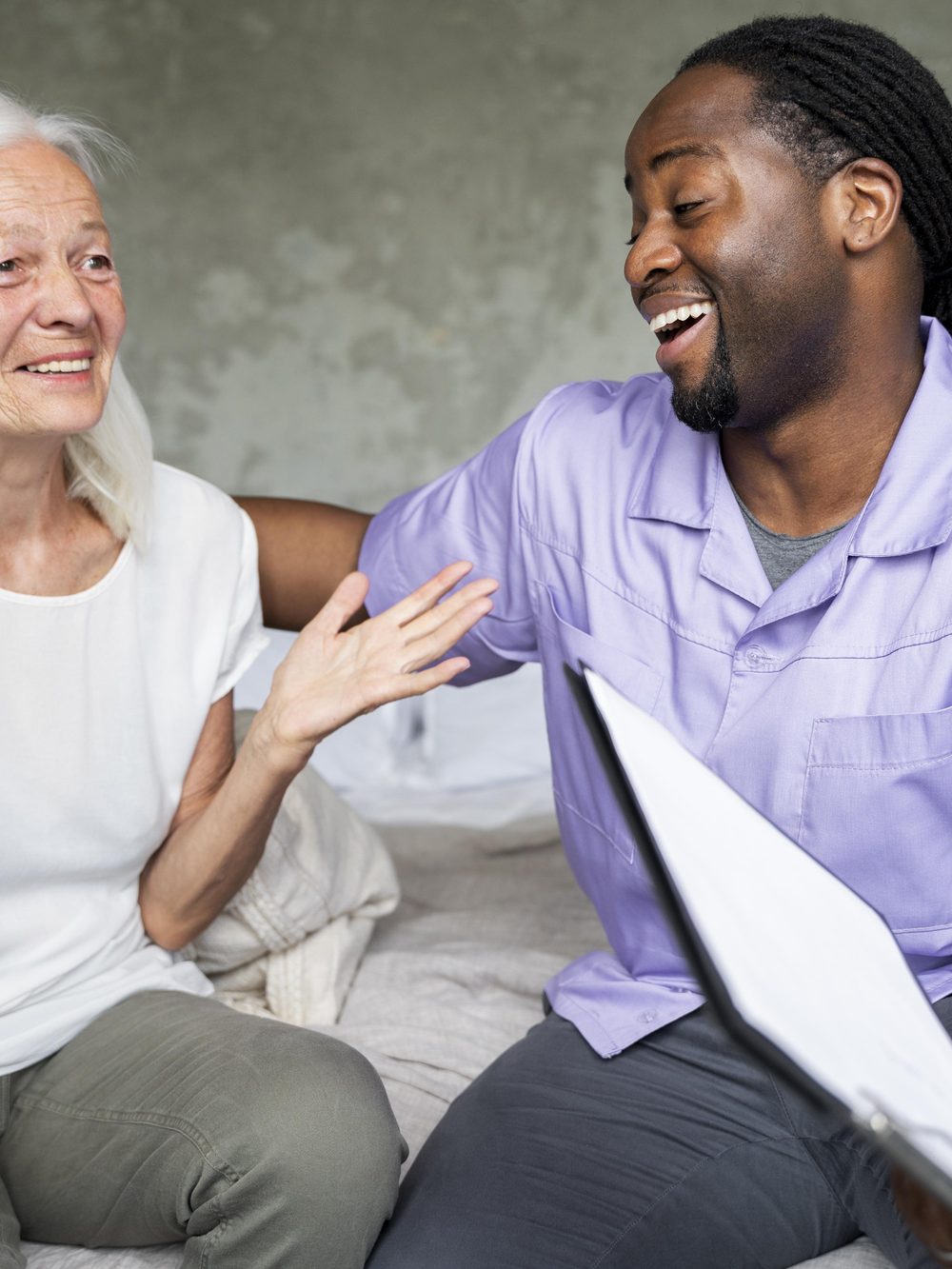 A carer sharing a joke with a resident on the sofa