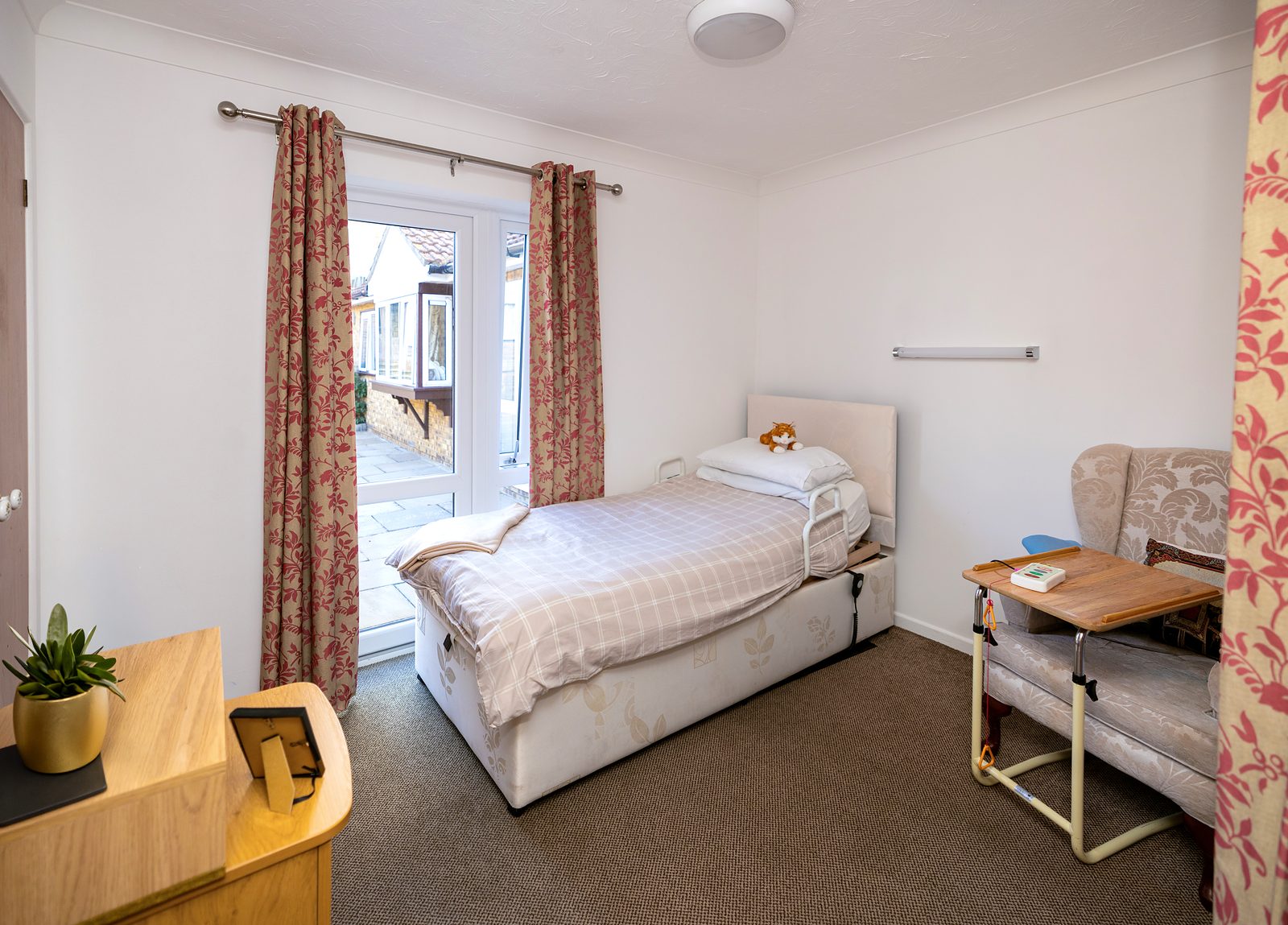 A single bedroom at Stronvar with an armchair and patio doors onto the courtyard