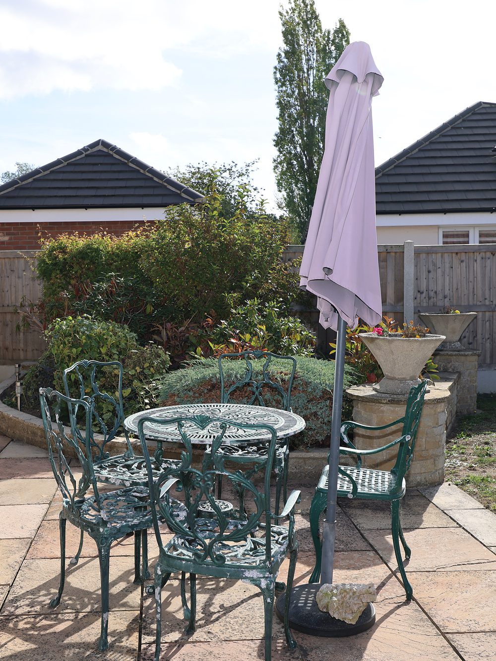 The garden patio at Stronvar, a table and chairs under a parasol among the shrubs