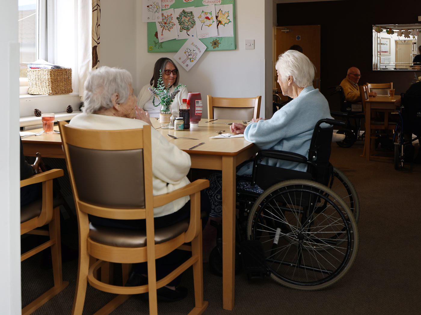 Residents chatting together around a table in the dining room